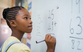 child at whiteboard doing math