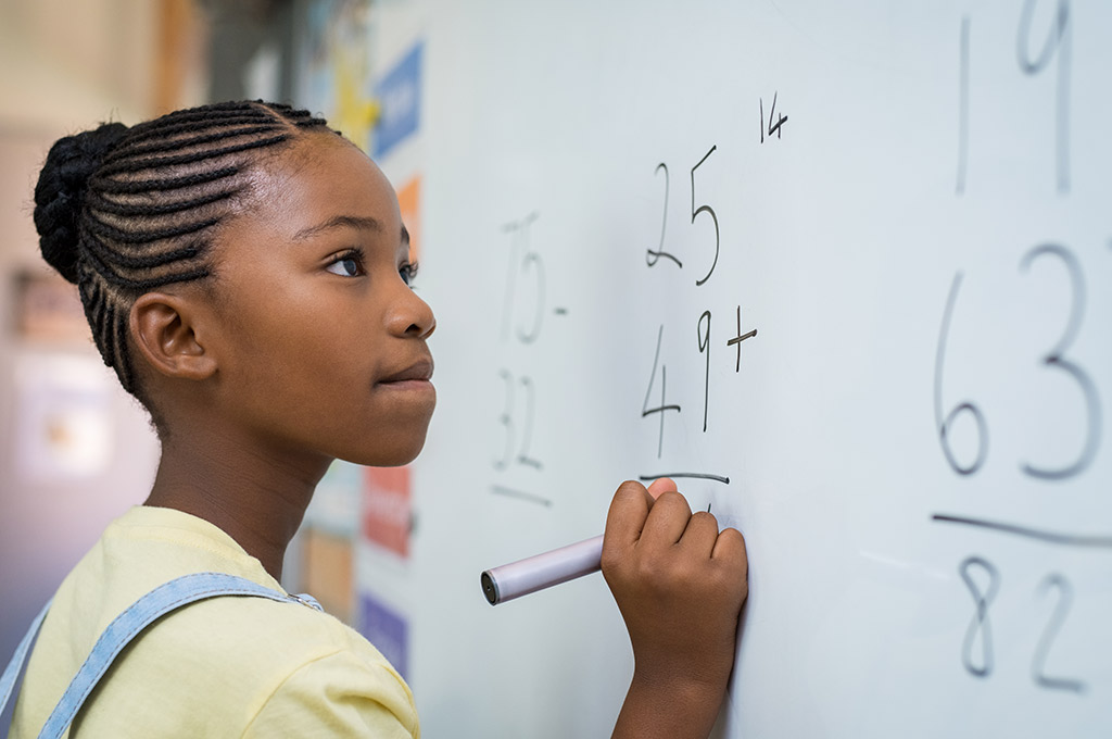 child at whiteboard doing math